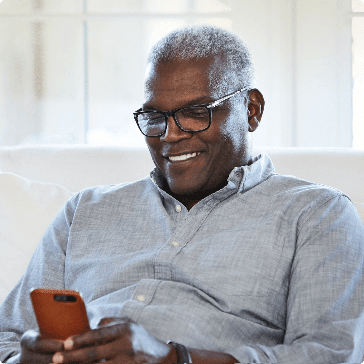Man with glasses looking at cell phone and smiling
