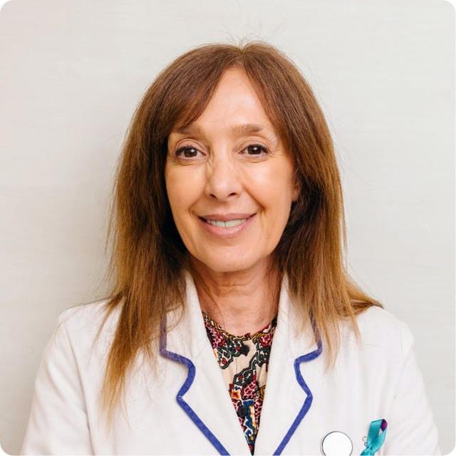 Portrait of a smiling female healthcare provider with straight brown hair, wearing a white lab coat with blue trim and a stethoscope.
